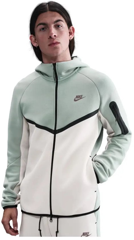 Model draagt een tweekleurig Nike Tech Fleece vest in mintgroen en gebroken wit met zwarte accenten en ritsen.