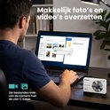 Man sluit witte KIEKZ camera aan op laptop met USB-C kabel om foto's over te zetten. Laptop toont zomerfoto's.