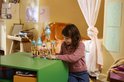 Meisje met bruin haar in roze vest bekijkt LEGO kasteel met 4 figuurtjes en bootje.