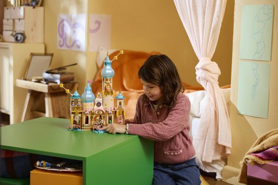 Meisje met bruin haar in roze vest bekijkt LEGO kasteel met 4 figuurtjes en bootje.