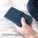 Blauw lederen telefoonhoesje met magnetische sluiting, vastgehouden door een hand.