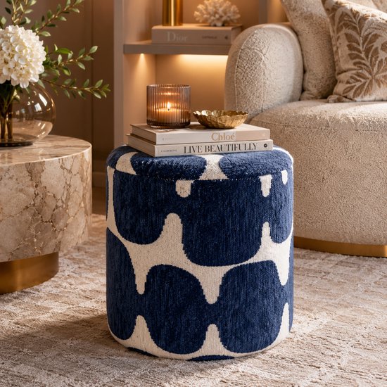 Pouf rond bleu et blanc à motif abstrait, dans un salon avec un fauteuil confortable.