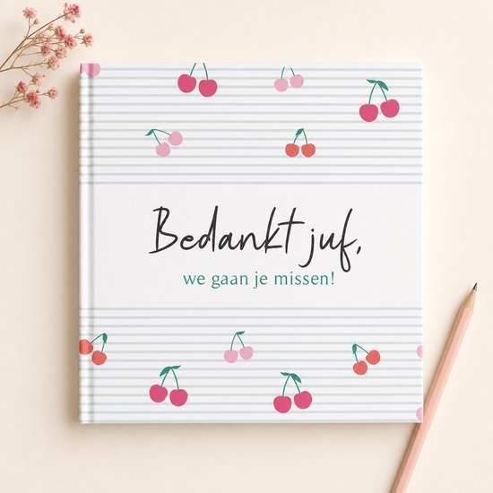 Een afscheidsboekje met de tekst 'Bedankt juf, we gaan je missen!' op een mintgroene gestreepte achtergrond met kersen. Gezien vanuit vogelperspectief met een potlood.