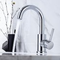 Chroomkleurige wastafelkraan in gebruik, met water dat uit de gebogen uitloop stroomt.
