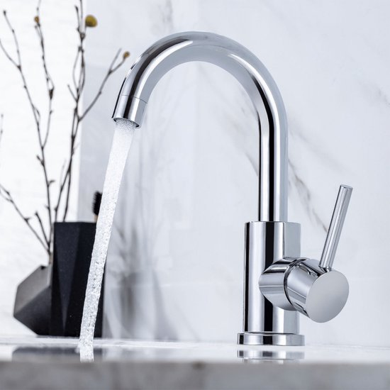 Chroomkleurige wastafelkraan in gebruik, met water dat uit de gebogen uitloop stroomt.