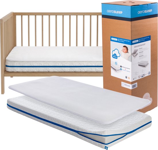 AeroSleep Evolution babymatras met 3D matrasbeschermer, naast een houten ledikant. De verpakking staat ernaast.