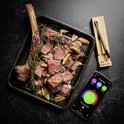 Een grote Tomahawk steak, gesneden, op een bakplaat met een Meater+ thermometer en een app op de telefoon.