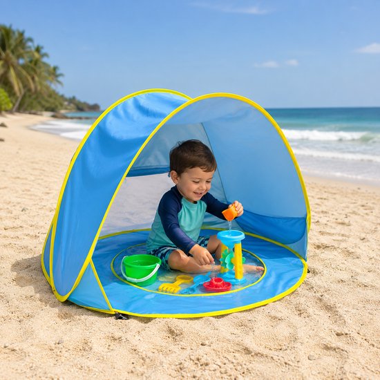 Jongen speelt in blauwe strandtent met zwembadje op het strand, met speelgoed.