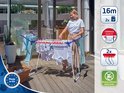 Een vrouw met een wit shirt en jeans op een terras, bij een droogrek met kleding.