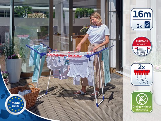 Een vrouw met een wit shirt en jeans op een terras, bij een droogrek met kleding.