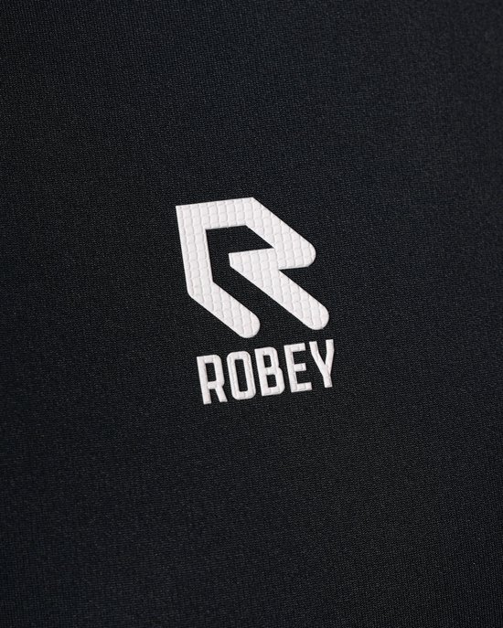 Close-up van het witte Robey logo op een zwarte poloshirt.