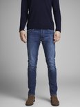 Man in donkerblauwe trui en blauwe jeans, deels in beeld.
