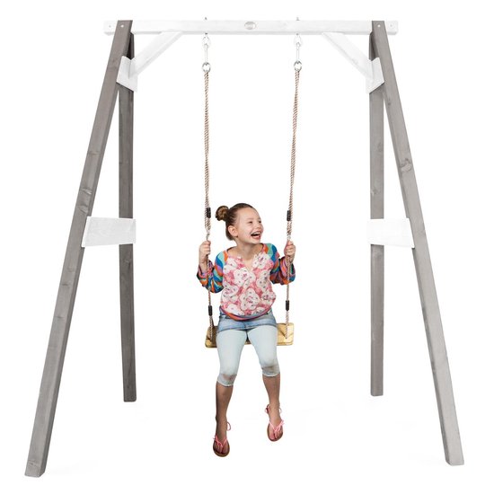 Meisje met gekleurde blouse en spijkerbroek, lachend op een houten schommel.