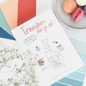 Het boek 'Trouwen doe je zo!' op een achtergrond van gekleurd papier, met macarons op de achtergrond.