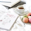 Een open boek met de tekst 'Trouwen doe je zo!', macaron's, een kopje thee en een bloem.