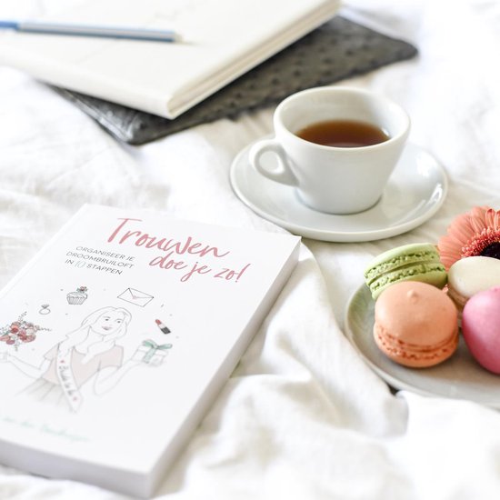 Een open boek met de tekst 'Trouwen doe je zo!', macaron's, een kopje thee en een bloem.