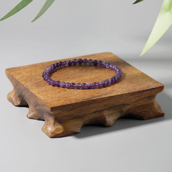 Paarse armband van amethistkralen op een houten display.