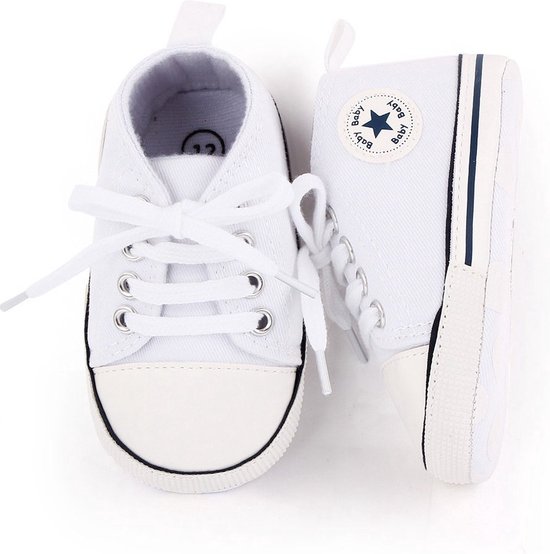 Twee witte babysneakers met veters, een blauw ster-logo, en een maat 12 label aan de binnenkant.