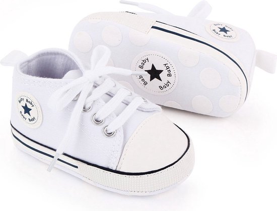 Twee witte babysneakers met veters, een blauw ster-logo, en antislipzolen met cirkels.