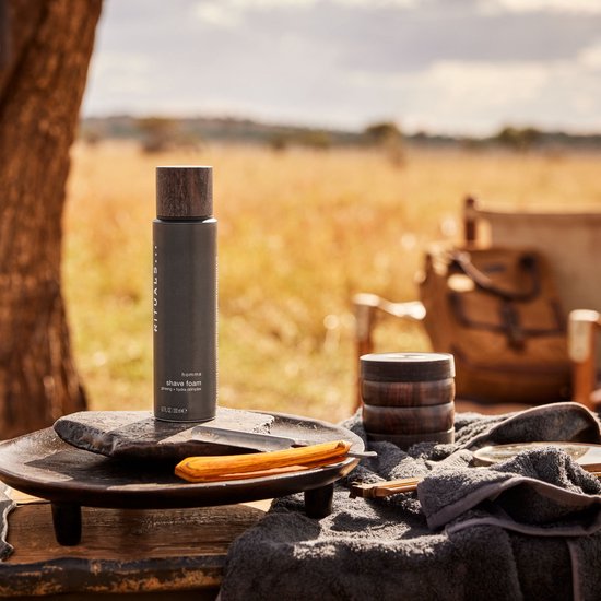 Rituals Homme scheerschuim spuitbus op tafel in een safari-setting, naast een scheermes.