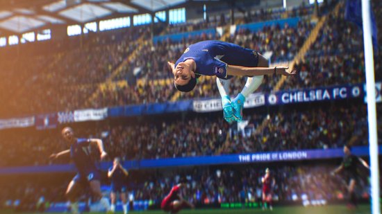 Voetballer in blauw shirt maakt een salto in de lucht tijdens een wedstrijd.