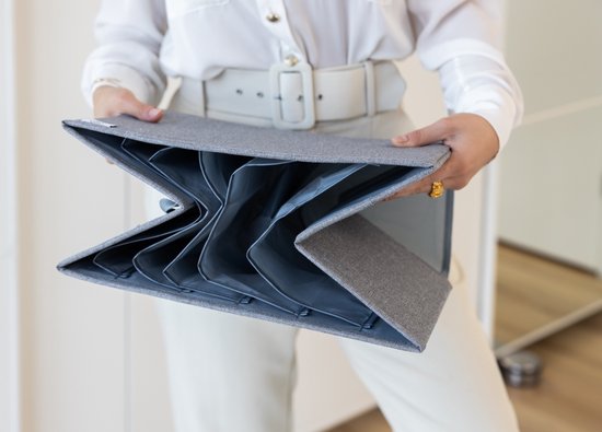 Femme tenant une boîte de rangement grise pliable en tissu avec 6 compartiments.