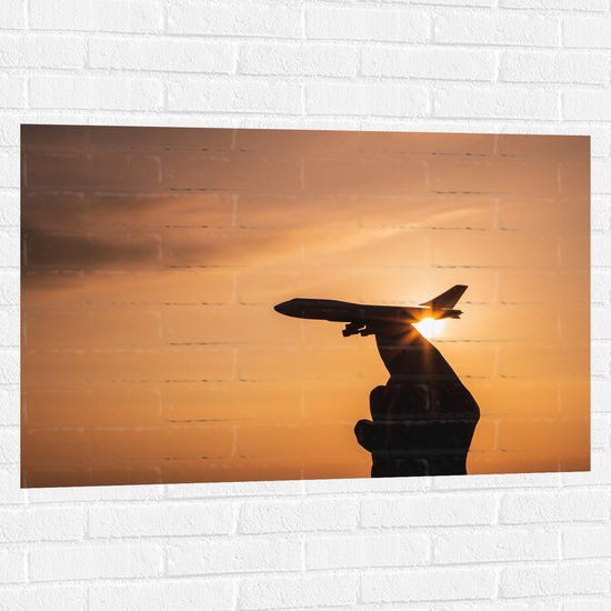 Muursticker - Speelgoed Vliegtuig in Mensenhand bij Zonsondergang - 105x70 cm Foto op Muursticker