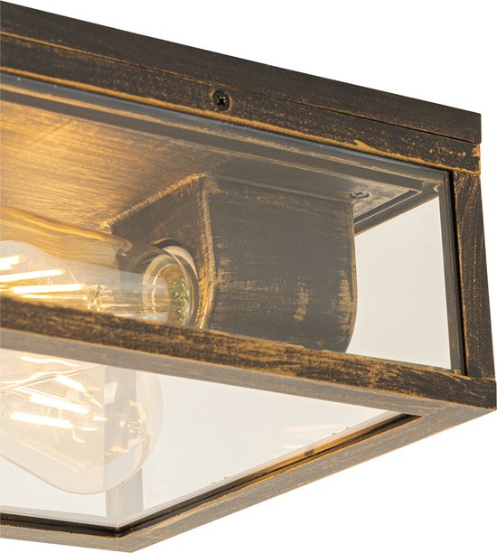 Detail van een vierkante buitenlamp met glazen zijkanten, verweerd gouden frame en een Edison-lamp.