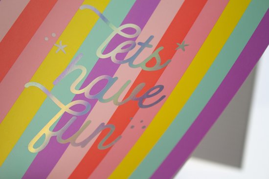 Close-up van folieletters 'lets have fun' op een gestreepte kaft.