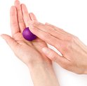 Handen rollen een kleine paarse bal klei in de handpalm.