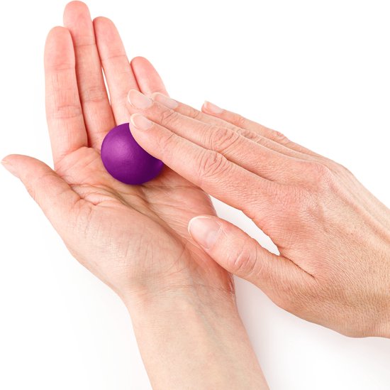 Handen rollen een kleine paarse bal klei in de handpalm.