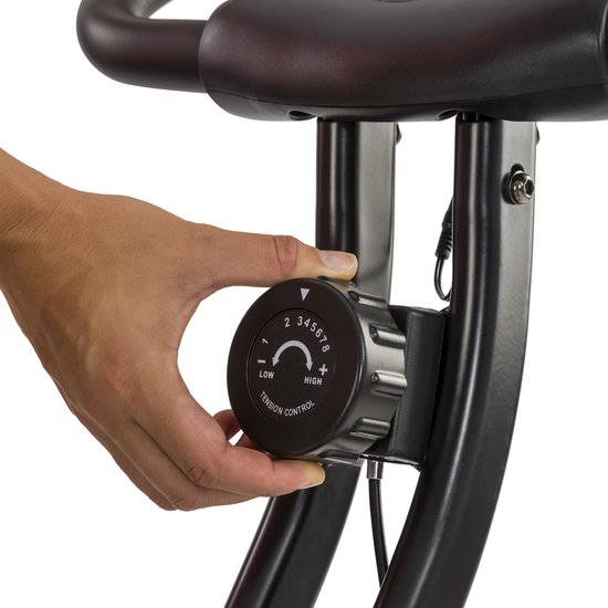 Hand draait aan de zwarte draaiknop voor weerstandscontrole op een hometrainer.