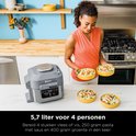 Vrouw met oranje topje serveert kip met pasta uit de grijze Ninja Speedi multicooker. 5,7 liter voor 4 personen.