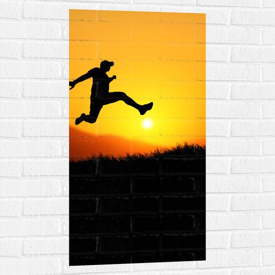 Muursticker - Silhouet van Springende Man bij Ondergaande Zon - 50x100 cm Foto op Muursticker
