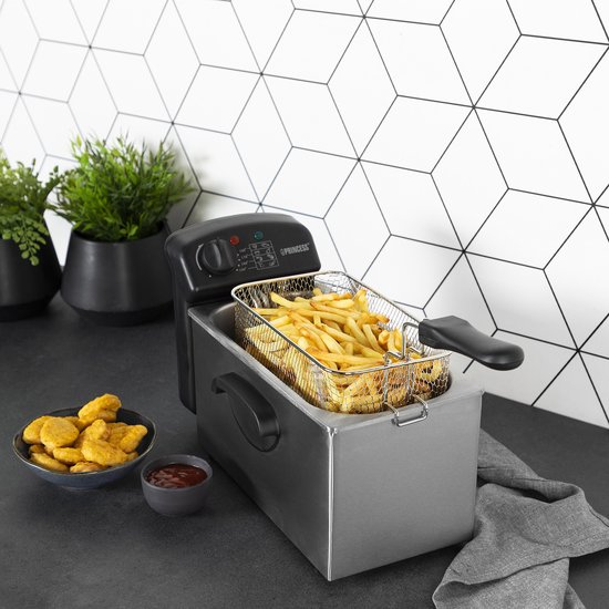 Roestvrijstalen frituurpan met mandje vol frietjes, geserveerd met kipnuggets en ketchup.