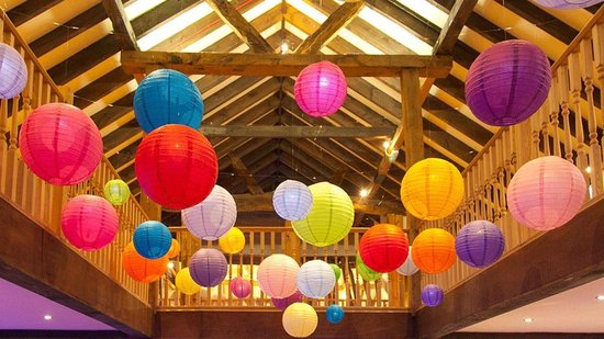 Veelkleurige lampionnen hangen op een zolder met houten balken.