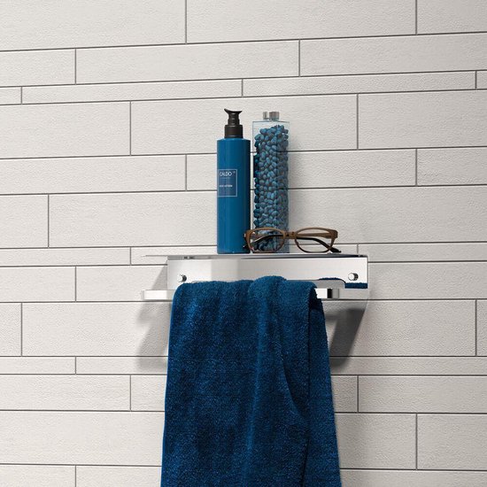 Étagère de douche chromée avec une bouteille de lotion bleue, des perles de bain bleues, des lunettes et une serviette bleue.