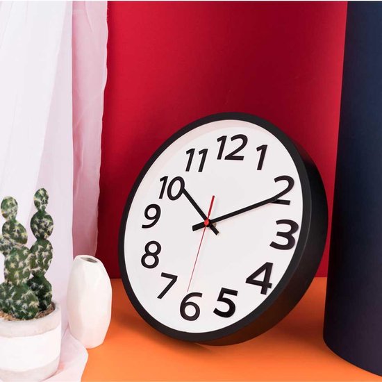 Witte wandklok met zwarte cijfers, op een oranje ondergrond, de klok wijst twee uur aan.