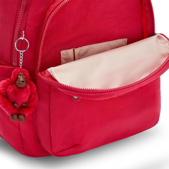 Sac à dos Kipling rouge avec poche avant ouverte et porte-clés singe rouge.