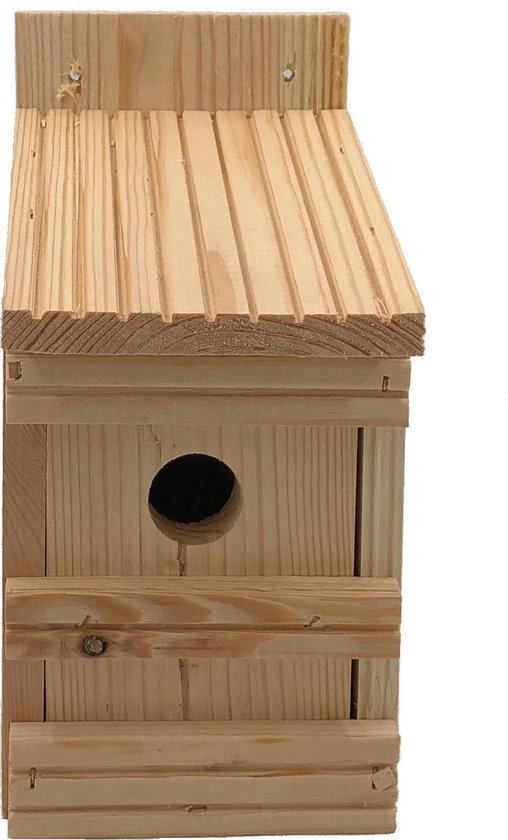 Vue latérale d'une maisonnette en bois avec toit incliné, entrée ronde et planches horizontales.