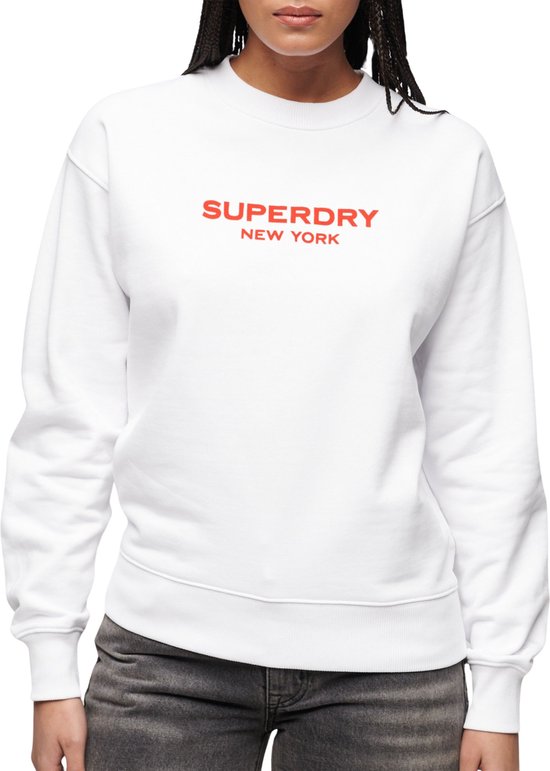Sweat blanc Superdry New York sur un mannequin, avec inscription rouge sur la poitrine.