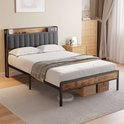 Lit dans une chambre, avec tête de lit grise, accents de bois, étagère de rangement et paniers sous le lit.