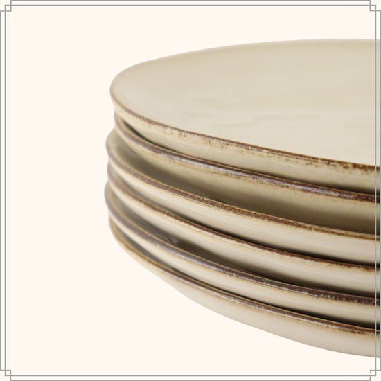 Stapel beige dinerborden met verweerde gouden randen, close-up.