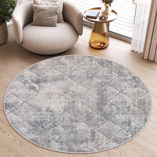 Rond grijs vloerkleed met een ingewikkeld diamantvormig patroon, gelegen in een woonkamer.