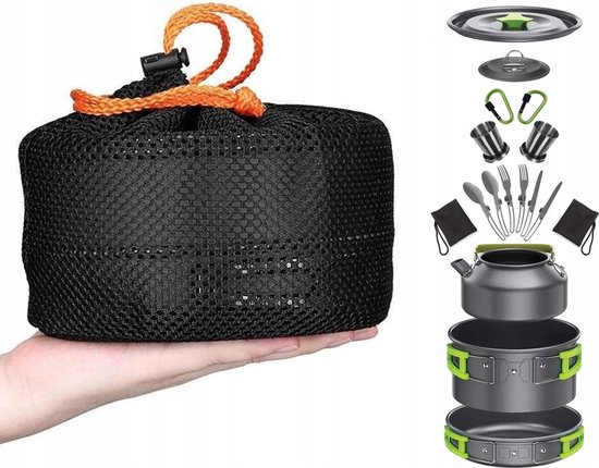 Een hand houdt een zwarte mesh opbergzak met oranje trekkoord vast. Naast de zak liggen de onderdelen van een kampeerservies, waaronder pannetjes, bestek en een waterkoker.