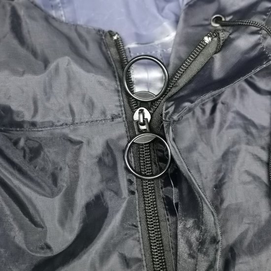 Sluiting met dubbele ritssluiting met ronde ringen op een zwarte regenponcho.