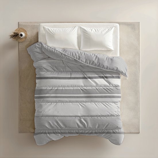 Dubbel dekbed met grijze en witte horizontale strepen, opgemaakt op een bed met twee witte kussens.