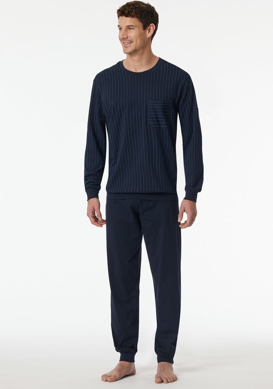 Man in donkerblauw pyjamaset met gestreept shirt en borstzakje.