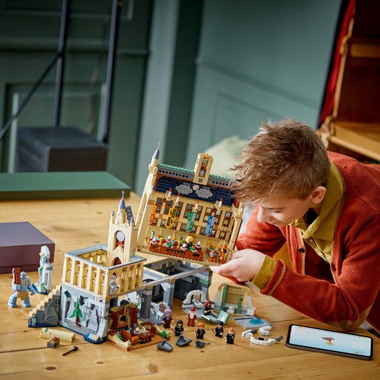 Un garçon construit le château de Poudlard La Grande Salle LEGO Harry Potter 76435, avec intérieur détaillé.