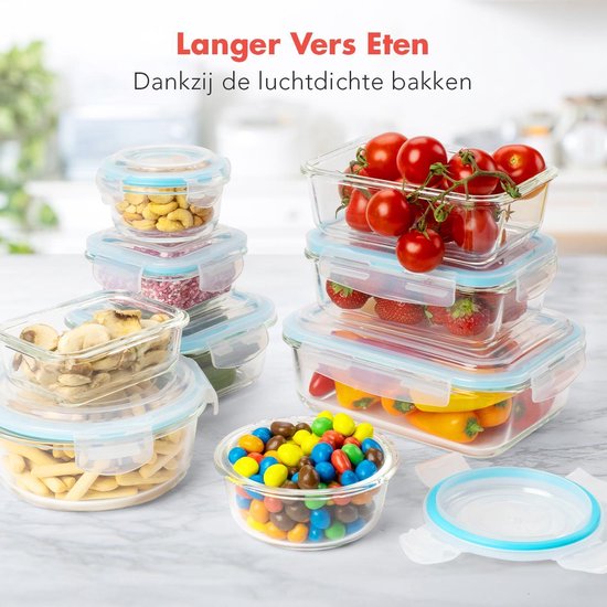 Glazen vershouddoosjes met fruit, groenten, noten en snoepjes op een marmeren aanrecht.